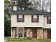 Two story townhouse featuring a stone facade, vinyl siding, and complementary dark brown shutters at 3628 Hopkins Ct, Powder Springs, GA 30127