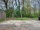 Spacious backyard featuring a concrete patio area, surrounded by mature trees and natural greenery at 3634 Hopkins Ct, Powder Springs, GA 30127