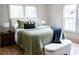 Cozy bedroom with natural light, a comfy bed with pillows, and an ottoman on the hardwood floor at 1395 Winburn Dr, East Point, GA 30344