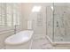 Bright bathroom featuring a soaking tub, marble tiled floors, glass-enclosed shower, and shuttered windows at 1418 Waterford Green Dr, Marietta, GA 30068