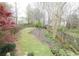 A tiered backyard with a wooden fence and natural foliage at 988 Vintage Pointe Dr, Lawrenceville, GA 30044