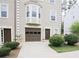 Exterior of a tan townhome with one car garage, bay window, and manicured landscaping at 988 Vintage Pointe Dr, Lawrenceville, GA 30044
