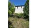 View of the white brick facade of a home with black trim seen through the overgrowth at 2085 Jones Phillips Rd, Dacula, GA 30019