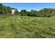 Grassy land featuring a partial view of a modern home surrounded by trees at 2085 Jones Phillips Rd, Dacula, GA 30019