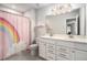 Bathroom featuring double sinks, ample vanity storage, rainbow shower curtain and a modern tiled floor at 214 Gaston Ct, Canton, GA 30115