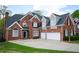 Brick home showing garage doors, a paved driveway, professional roof, and well-maintained lawn at 2165 Sugarstone Ct, Lawrenceville, GA 30043