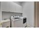 Laundry room with modern washer and dryer and white cabinets at 2165 Sugarstone Ct, Lawrenceville, GA 30043