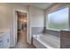 Bathroom featuring a large soaking tub next to a frosted window and view into walk-in closet at 419 Murphy Ave, Canton, GA 30114