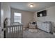 Bedroom features a crib, white dresser, armchair, area rug, and mounted television at 419 Murphy Ave, Canton, GA 30114