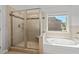 Bright bathroom features a soaking tub next to a large glass shower with tiled walls and accents at 4585 Woodland Bank Blvd, Buford, GA 30518