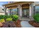 Inviting front entrance with stone accents, a covered porch, and professionally landscaped shrubbery at 4585 Woodland Bank Blvd, Buford, GA 30518
