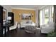 Bright living room features a mustard accent wall, dark hardwood floors, and large windows at 4585 Woodland Bank Blvd, Buford, GA 30518