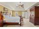 Spacious main bedroom with a tray ceiling, ceiling fan, and large dresser for optimal storage at 9860 Hunt Club Way, Johns Creek, GA 30022
