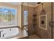 Bathroom featuring glass enclosed shower, soaking tub with jet streams, tiled surround, and sunny window view at 9860 Hunt Club Way, Johns Creek, GA 30022