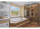 Relaxing bathroom with soaking tub, tiled shower, and shelves for towels offering a luxurious spa-like feel at 9860 Hunt Club Way, Johns Creek, GA 30022