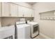 Functional laundry room with sink, washer, dryer, and storage cabinets at 201 Saddle Rd, Alpharetta, GA 30009
