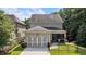 Home's back exterior showing a two-car garage and screened porch, all surrounded by green trees at 201 Saddle Rd, Alpharetta, GA 30009