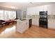 Bright kitchen features white cabinets, stainless appliances, island with sink, and hardwood floors at 2815 Cambridge Hills Rd, Cumming, GA 30041