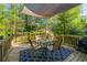 Outdoor back deck with seating area, shade cover, and a scenic view of the wooded backyard at 3988 Centennial Trl, Duluth, GA 30096