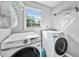 Convenient laundry room featuring new white Samsung washer and dryer, natural light, and storage shelves at 3988 Centennial Trl, Duluth, GA 30096