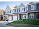 Charming townhome featuring a gray exterior, brick accents, attached garage, and manicured landscaping at 2162 Spikerush Way, Buford, GA 30519