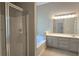 Modern bathroom features a glass-door shower, bathtub, and large vanity with a large mirror at 225 Mountain Vista Blvd, Canton, GA 30115
