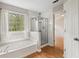 Bathroom featuring a soaking tub, glass-enclosed shower, large window and hardwood floors for added comfort at 3025 Kaley Nw Dr, Kennesaw, GA 30152