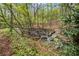 A peaceful, rocky creek flows through the trees and foliage in this wooded landscape, adding natural beauty and tranquility to the property at 3025 Kaley Nw Dr, Kennesaw, GA 30152