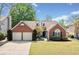 Charming brick home with a well-manicured lawn, mature trees, and an attached two-car garage at 1483 Chamirey Sw Dr, Marietta, GA 30008