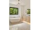 Bright bathroom featuring a standalone tub, modern lighting, and a large window with a beautiful nature view at 1501 Harts Mill Ne Rd, Brookhaven, GA 30319