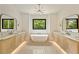 Symmetrical bathroom with dual vanities, freestanding tub, modern lighting, and backyard views at 1501 Harts Mill Ne Rd, Brookhaven, GA 30319