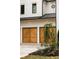 View of the wooden three-car garage doors, painted brick exterior, and dark trim windows at 1501 Harts Mill Ne Rd, Brookhaven, GA 30319
