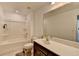 Well lit bathroom featuring dark vanity, tub/shower combo, toilet, large mirror, and light tile floor at 5530 Bower Pl, Cumming, GA 30028