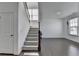 Staircase in a brightly lit foyer featuring hardwood floors, carpeted stairs, and white walls at 5530 Bower Pl, Cumming, GA 30028
