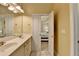 Bright bathroom featuring double sinks, cream cabinets, and an open door to the Primary bedroom at 2920 Olde Towne Pkwy, Duluth, GA 30097