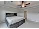 Spacious bedroom features a tray ceiling with fan and a gray bed with storage and headboard with shelving at 4650 Sandy Creek Dr, Cumming, GA 30028