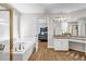 Bright bathroom featuring a large soaking tub, granite countertops, and modern fixtures and wood flooring at 3139 Players Dr, Jonesboro, GA 30236