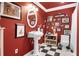 Charming bathroom featuring bold red walls, pedestal sink, black and white checkered floors, and decorative wall art at 561 Valleyside Dr, Dallas, GA 30157