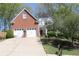 Traditional brick home with a two-car garage, manicured lawn, and mature trees at 561 Valleyside Dr, Dallas, GA 30157