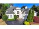 Elegant white home featuring arched windows, manicured landscaping, and a paved driveway at 7080 Greatwood Trl, Alpharetta, GA 30005