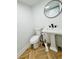 Cozy bathroom featuring a toilet, pedestal sink and round mirror above the sink at 102 Adrian Nw Pl, Atlanta, GA 30327