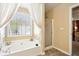 Bright bathroom featuring a soaking tub with window and curtains, and a glass-door shower at 2523 Bancroft Way, Buford, GA 30519