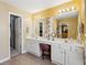 Bright bathroom featuring dual vanities, a large mirror, and a separate makeup area with comfortable seating at 2523 Bancroft Way, Buford, GA 30519