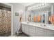 Bright bathroom featuring dual vanities, a large mirror, and a shower with a colorful curtain at 2523 Bancroft Way, Buford, GA 30519