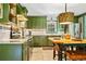 Kitchen boasts green cabinetry, stainless steel appliances, and an island table with stylish light fixture at 3919 Evans Rd, Cumming, GA 30040