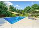 A backyard pool with lounge chairs and a sunshade surrounded by lush greenery at 3919 Evans Rd, Cumming, GA 30040