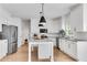 Well-lit kitchen featuring stainless appliances, white cabinets, island, and hardwood floors at 4414 Aldenham Way, Suwanee, GA 30024