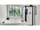 Bright bathroom featuring a soaking tub with jets, a shower with a glass door, and a large window with natural light at 4414 Aldenham Way, Suwanee, GA 30024