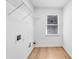 Bright laundry room featuring hardwood floors and a metal shelf on the wall at 4414 Aldenham Way, Suwanee, GA 30024
