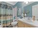 Well-lit bathroom with a sink and a shower/bathtub combo and a blue and white shower curtain at 4531 Cedar Dr, Loganville, GA 30052
